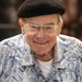 photo of a smiling man with a Hawaiian style shirt, glasses, and a black beret