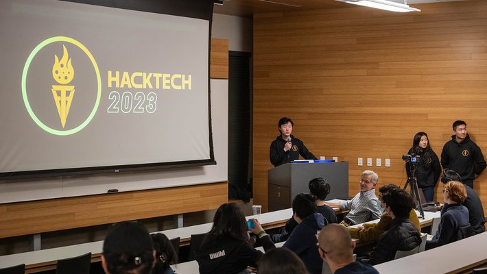 Aaron Zhao speaks in front of a screen that reads "Hacktech 2023"