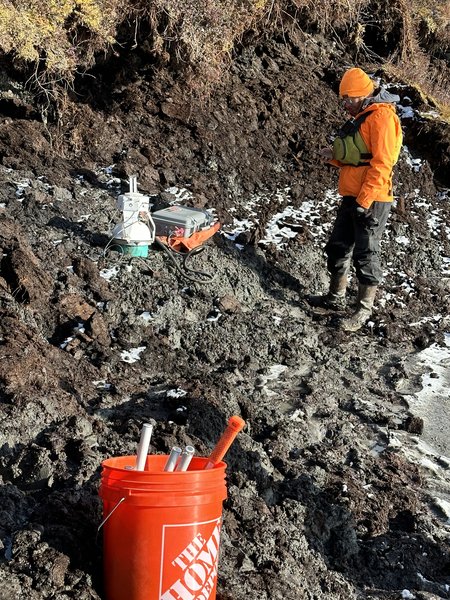 Scientists stand outside near rocky soil.