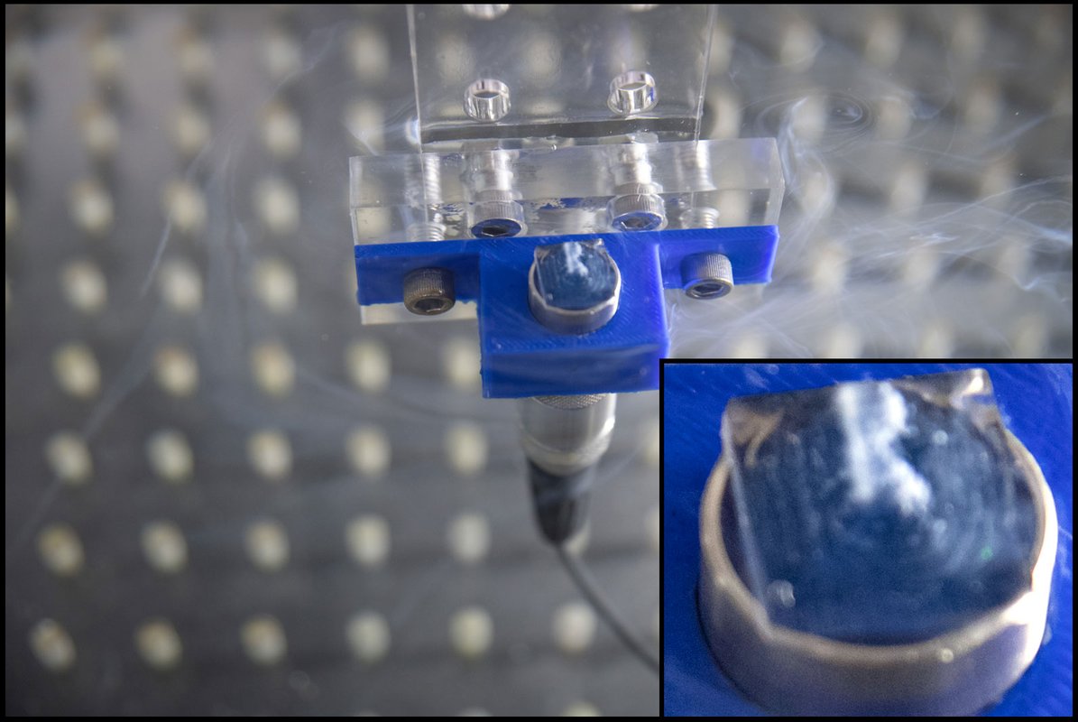 An ultrasound apparatus arranges genetically modified bacteria into the shape of the letter R in solution. The R is small and floats above a plastic bit.