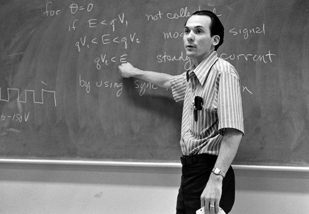 A man standing next to a blackboard