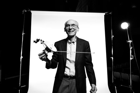 A smiling man holding a small model of a spacecraft